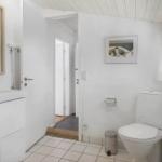 Bathroom with toilet, sink, and mirror. Window and door visible.