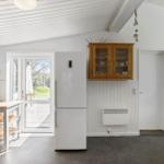 Kitchen with refrigerator, wooden cabinets, and table. Passage to the terrace.