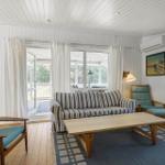Living room with sofa, chairs, and table. Doorways to terrace and garden.