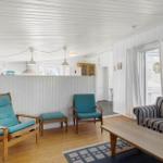 Living room with sofa, chairs, and wooden floor. White walls and ceiling.