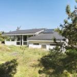 House with terrace and solar panels on grassy lawn.