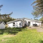 White vacation home with terrace, garden, and small shed under trees.