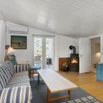 Living room with sofa, fireplace, and TV. Wooden floor and large windows.