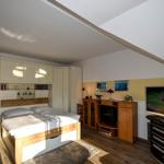 Schlafzimmer mit Bett, Schränken und Fernseher unter Dachschräge.