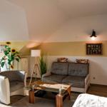 Wohnzimmer mit Sofa, Sessel und Glas-Tisch unter schrägen Decken.