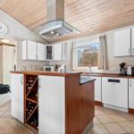 Kitchen with wooden ceiling, white cabinets, and central island with wine cellar.