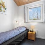 A bedroom with bed, nightstand, and window. Wooden ceiling and wall art.