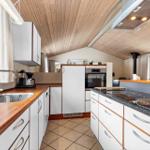 Kitchen with wooden ceiling, white cabinets, and stainless steel sink.