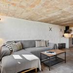 Wohnbereich mit Sofa, Couchtisch und Küche unter Steindecke.