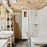 Bad mit Dusche, Waschbecken und Holzregal unter Ziegeldecke.