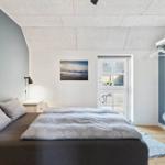 Schlafzimmer mit Bett, Kleiderständer und Tür zum Außenbereich.