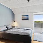 Schlafzimmer mit Bett, Decke, Tür zum Balkon und Wandbild.