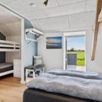 Schlafzimmer mit Doppelbett und Krippenbett. Tür führt auf Terrasse mit Blick auf Feld.