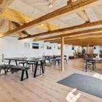 Großes Wohn- und Esszimmer mit Holzbalken, Tischen und Stühlen.