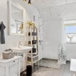 Badezimmer mit Dusche, Waschbecken und Fenster.