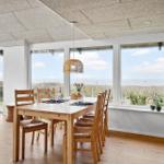 Esszimmer mit Tisch, Stühlen und Meerblick durch große Fenster.