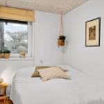 Ein Schlafzimmer mit Bett, Fenster und Pflanzen.