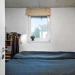 Schlafzimmer mit Bett, Fenster und Bücherregal.
