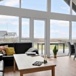 Wohnzimmer mit großem Fensterblick auf Landschaft und Terrasse mit Gartenmöbeln.
