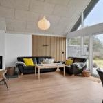Wohnzimmer mit Sofa, Kamin und großen Fenstern.