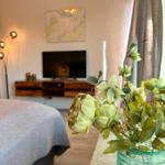 Schlafzimmer mit Bett, Fernseher und Blumen im Vordergrund.