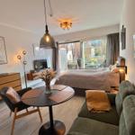 Ein Raum mit Schlafbereich, Wohnbereich und Essplatz. Große Fensterfront mit Blick auf Balkon.