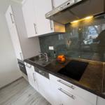 Küche mit weißen Schränken, dunklem Arbeitsplatz und Edelstahlspüle.