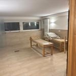 Sauna mit Holzliegen und Fenstern. Boden und Wände sind gefliest.