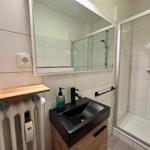 Badezimmer mit Dusche, Waschbecken und Spiegel