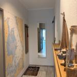 Flur mit Seekartenwand, Spiegel und Holzbank mit Segelmodell.