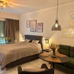 Schlafzimmer mit Bett, Sofa und Tisch. Wanddekoration und Fenster mit Jalousien.