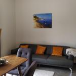 Wohn- und Essbereich mit Sofa, Tisch und Küchenzeile. An der Wand hängen zwei Bilder.