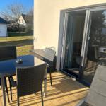 Terrasse mit Tisch, Stühlen und Schiebetür zum Innenraum.