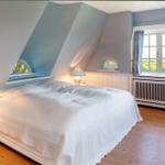 Schlafzimmer mit Dachschrägen, großem Bett und Fenster mit Blick.