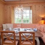 Esszimmer mit Holzwand, Bank mit orangefarbenem Stoff und Tisch mit Geschirr.