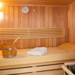Sauna mit Holzbank, Eimer und Handtuch.