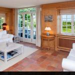Wohnzimmer mit Holzwand, Terrasse und Meerblick durch Fenster.