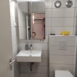 Badezimmer mit Waschbecken, Spiegel, Toilette und Dusche.