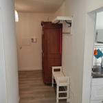 Flur mit Kleiderschrank, Stuhl und Blick in die Küche.