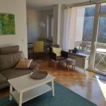 Wohnzimmer mit Sofa, Couchtisch und Balkon. Holzboden und große Fenster.