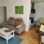 Wohnzimmer mit Sofa, Sessel und Essbereich. Holzfußboden und Wandbild.