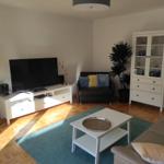 Wohnzimmer mit Sofa, Fernseher und Schrank.