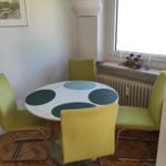 Rundtisch mit vier grünen Stühlen und Fenster