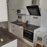 Küche mit Herd, Dunstabzug, Spüle und Mikrowelle.