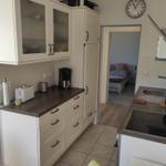 Küche mit Dunstabzug, Kochfeld und Arbeitsfläche. Durchgang in Schlafzimmer mit Bett.