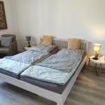 Schlafzimmer mit Doppelbett, zwei Nachttischen und Sessel.