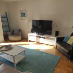 Wohnzimmer mit Sofa, Fernseher und Holzboden.