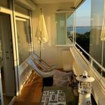 Terrasse mit Liegestühlen und Meerblick. Gelber Sonnenschirm und Tisch mit Dekoration.