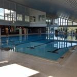 Großes Hallenbad mit Schwimmbecken und Glasfronten.