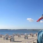 Strand mit Strandkörben und französischer Flagge am Horizont.